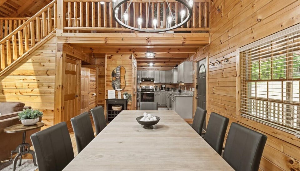 The open-concept layout flows seamlessly into a fully remodeled kitchen, boasting sleek gray cabinetry, stainless steel appliances, and granite countertops. Cedar walls, exposed beams, and loft to second level is visible.