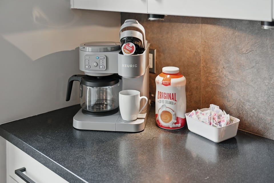 Start your day right with a Keurig dual coffee maker, mugs, creamer, and sweetener—all ready to go at your personal coffee station.