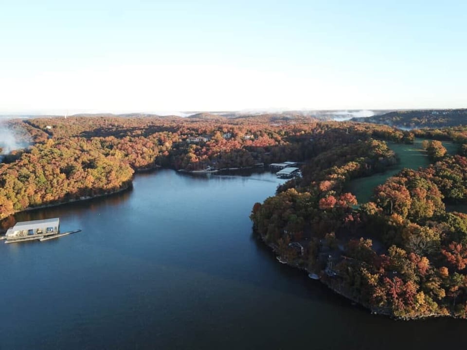 This expansive aerial view showcases the stunning Lake of the Ozarks, surrounded by vibrant fall foliage, offering a truly picturesque setting.