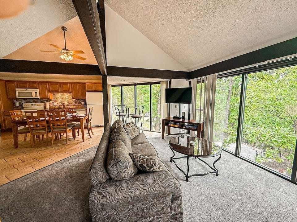 Enjoy a spacious living room with floor-to-ceiling glass windows, offering breathtaking views of nature. Perfect for family gatherings, game nights, and relaxation.