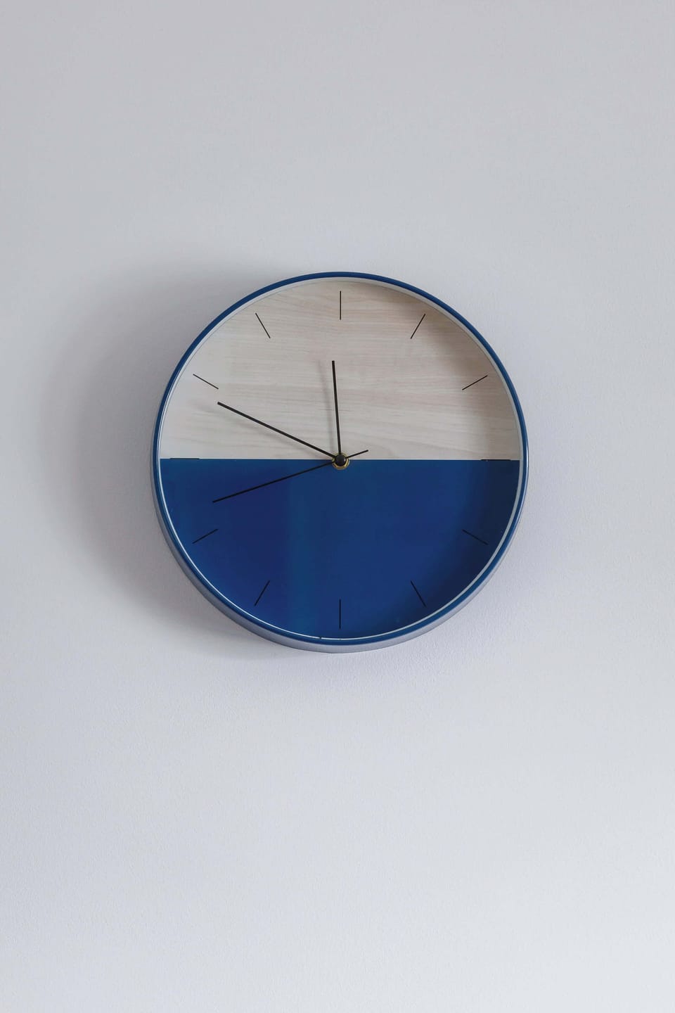 Minimalist wall clock on plain white wall.