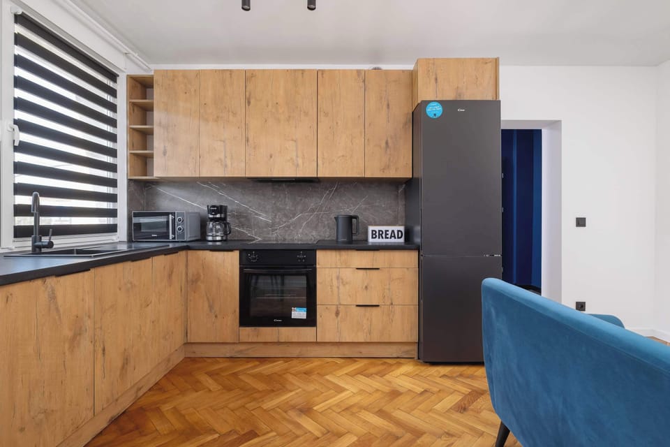 Modern kitchen with wooden cabinets, black countertops, built-in appliances.