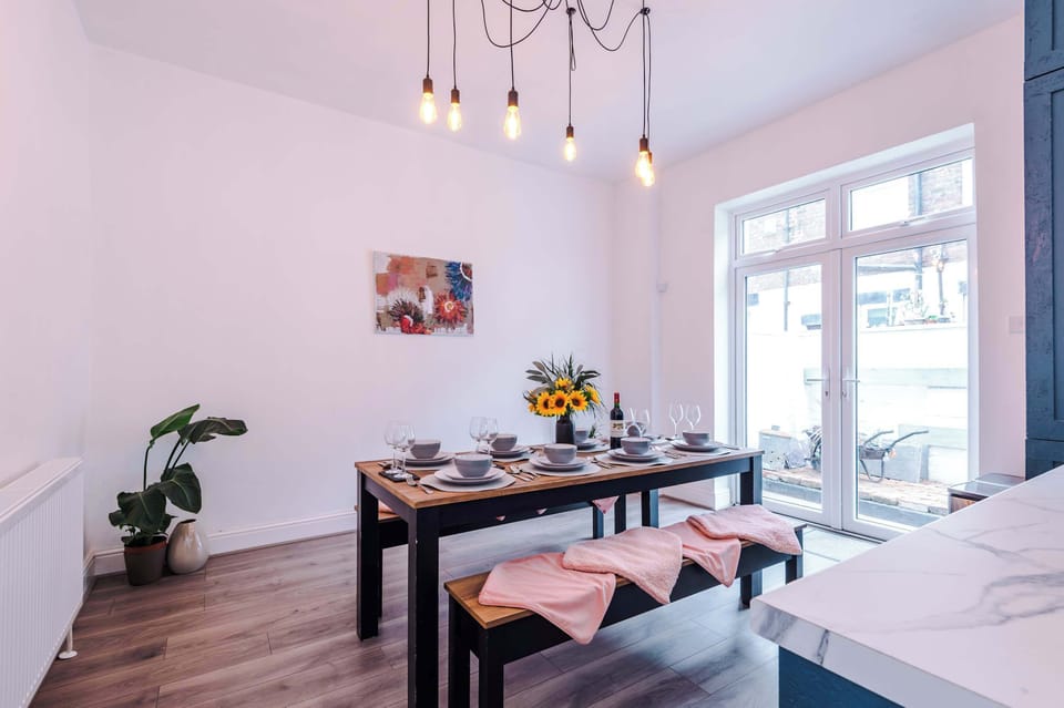 Enjoy meals in this modern dining space featuring a neatly set table, sleek lighting, and plenty of natural light. Ideal for relaxed breakfasts, shared dinners, and spending quality time together