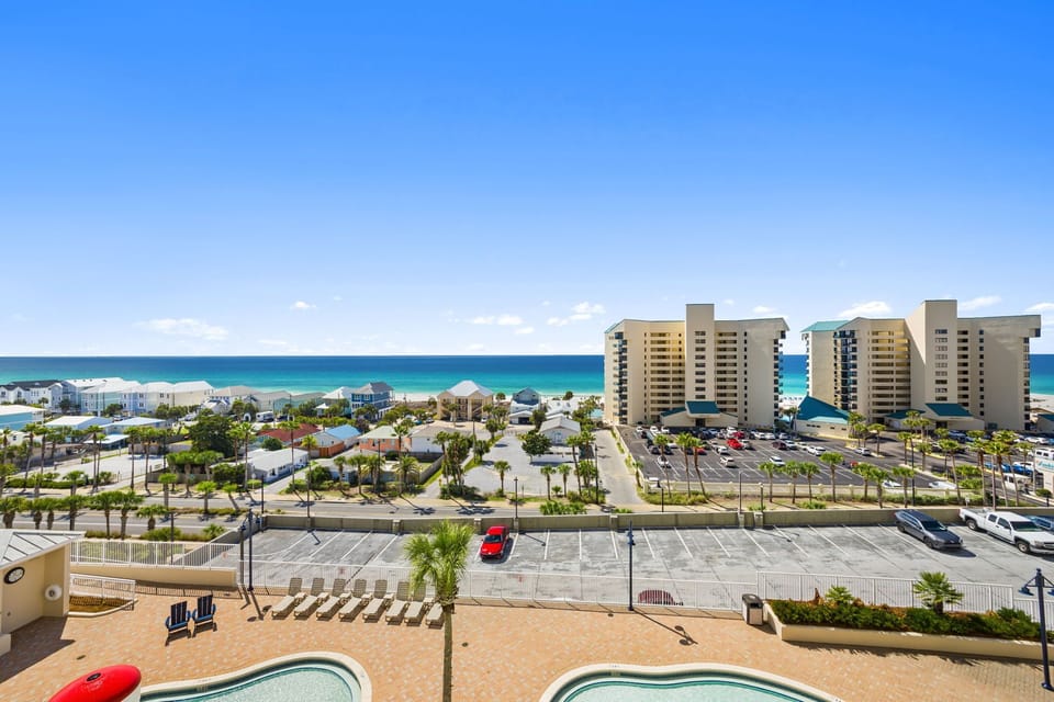 Ocean view from a high-rise balcony overlooking nearby buildings and the beach.