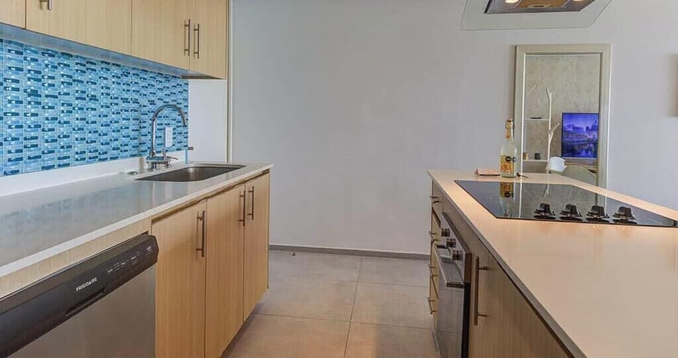 Sleek kitchen w/ wood cabinets, blue tile backsplash & stainless appliances