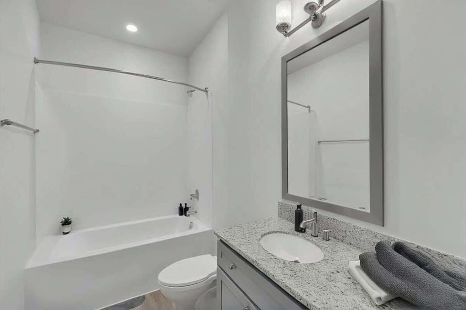 A bright and modern bathroom featuring a sleek vanity, a spacious bathtub with a shower, and stylish finishes. Clean and inviting, perfect for a refreshing start to your day or a relaxing unwind.