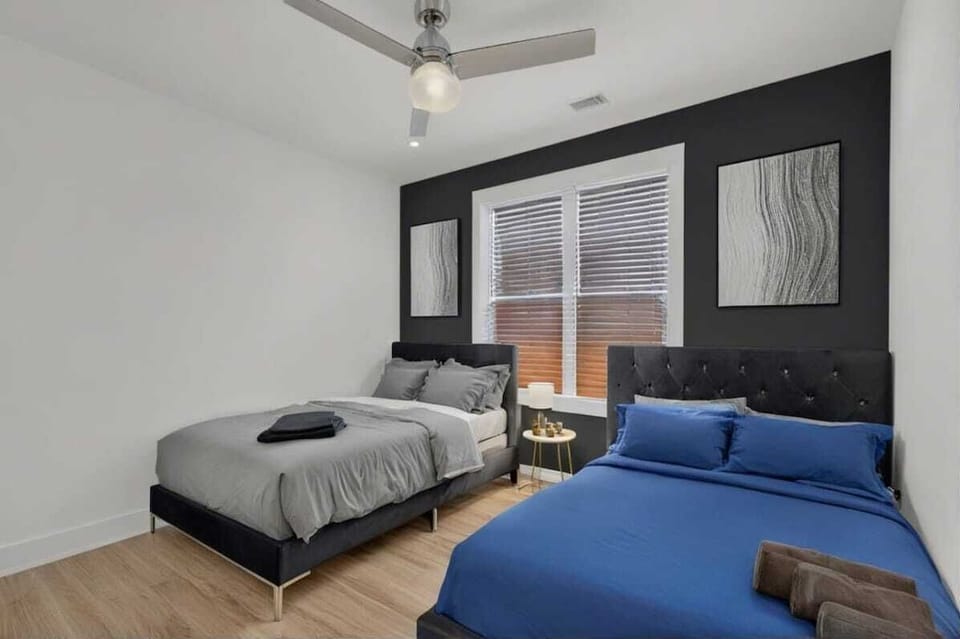 A spacious and stylish bedroom featuring two cozy beds, a modern black accent wall, and elegant decor. Ideal for families or friends, offering comfort, soft lighting, and plenty of natural light.