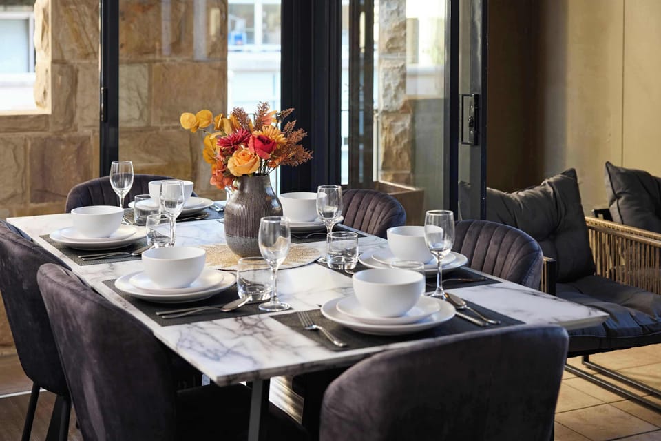 Elegant Dining Area with Natural Light, A beautifully set dining table perfect for family meals or entertaining, framed by sunlit glass doors.