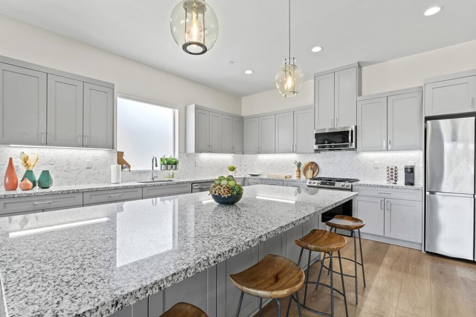 Sleek kitchen w/ large island, bar seating & stainless steel appliances