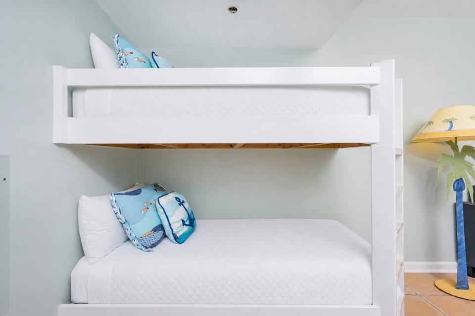 Bright and cheerful twin bunk beds with nautical-themed pillows, perfect for kids enjoying a beach getaway