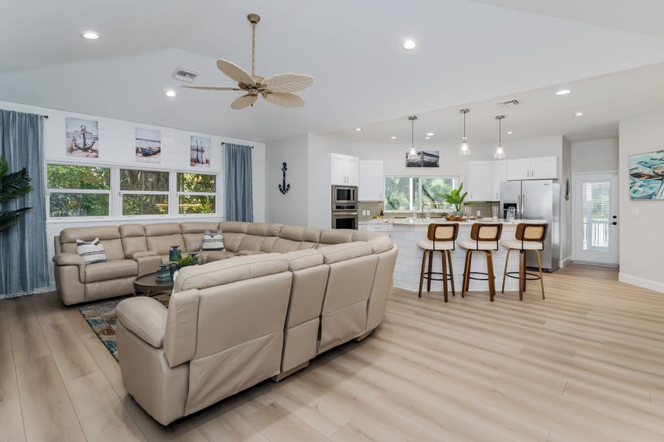 Step into your bright, airy retreat where coastal charm meets modern comfort. Sink into the plush sectional sofa while ocean breezes flow through, and gather around the sleek kitchen island for memorable meals together.