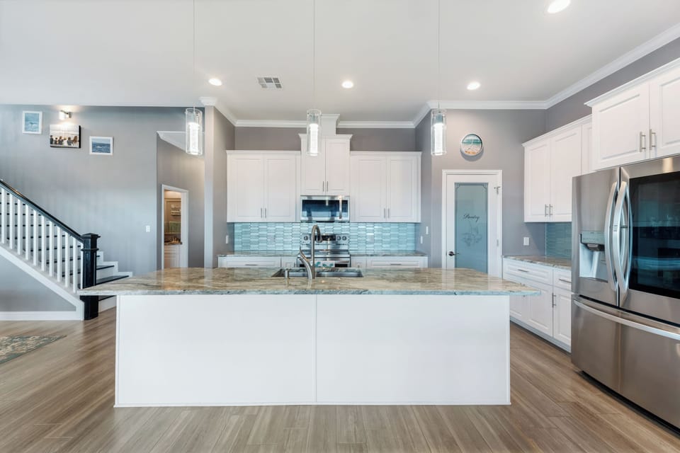 The kitchen has a large island, stainless appliances, and granite counters.