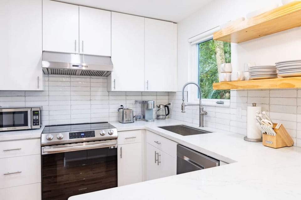 Sleek and fully equipped kitchen featuring stainless steel appliances, open shelving, and stylish finishes