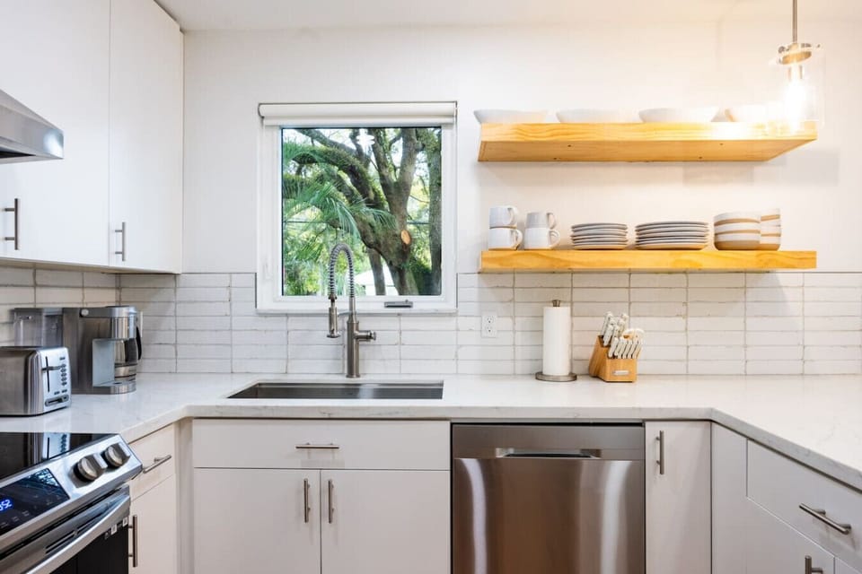 Bright and modern kitchen with open shelving, a large sink, and beautiful outdoor views.