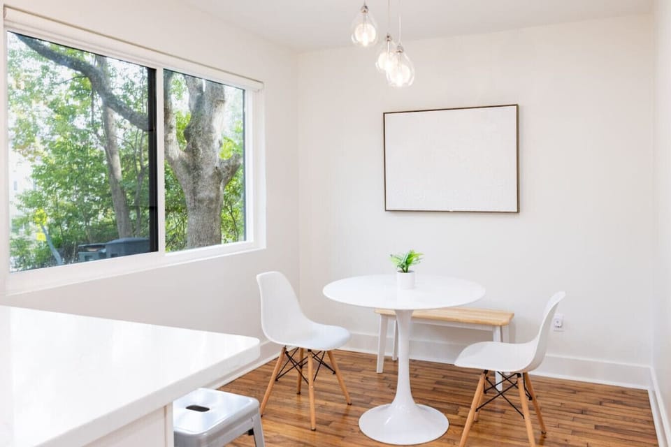 Cozy dining nook with large windows, chic pendant lighting, and a stylish table for gathering and meals.