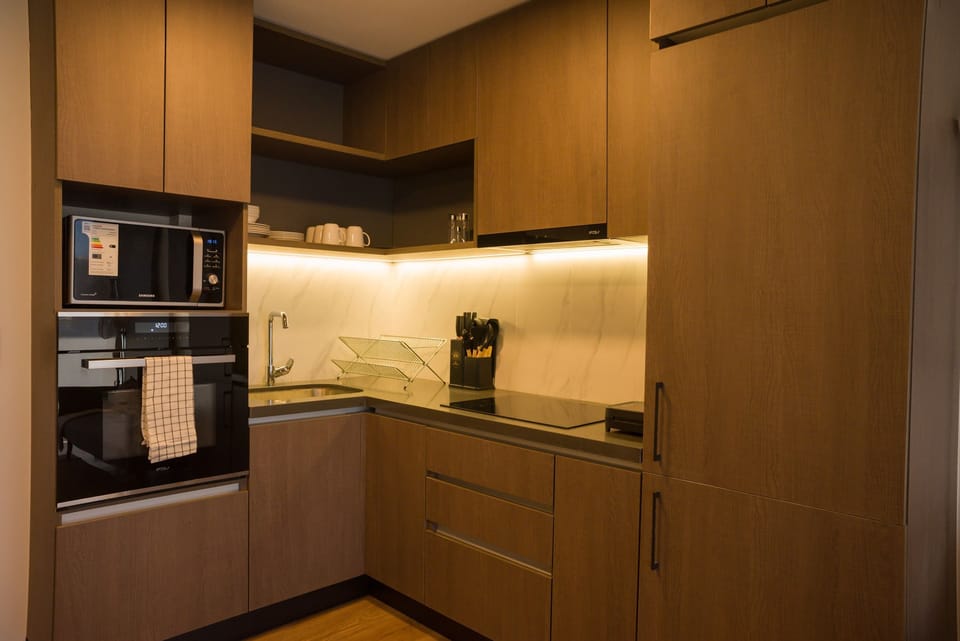 Sleek and modern kitchen with all essentials for your culinary needs, featuring stylish wooden cabinetry and ambient lighting.