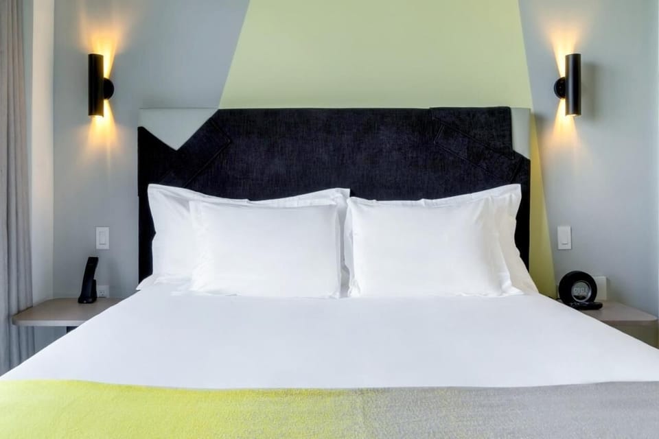 Drift off on crisp linens beneath stylish, modern headboard lighting.
