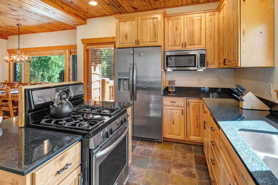 The well equipped kitchen has stainless appliances, black granite counters, and wood cabinets.