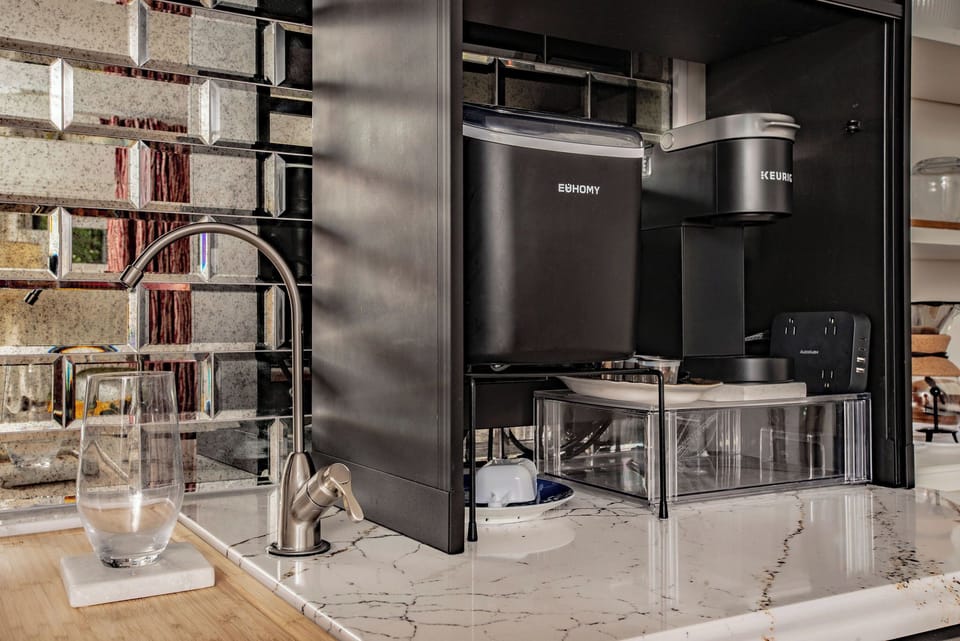 Close up of our kitchenette, featuring a mini-fridge, sink, ice maker, Keurig coffee maker, and toaster oven / air fryer.
