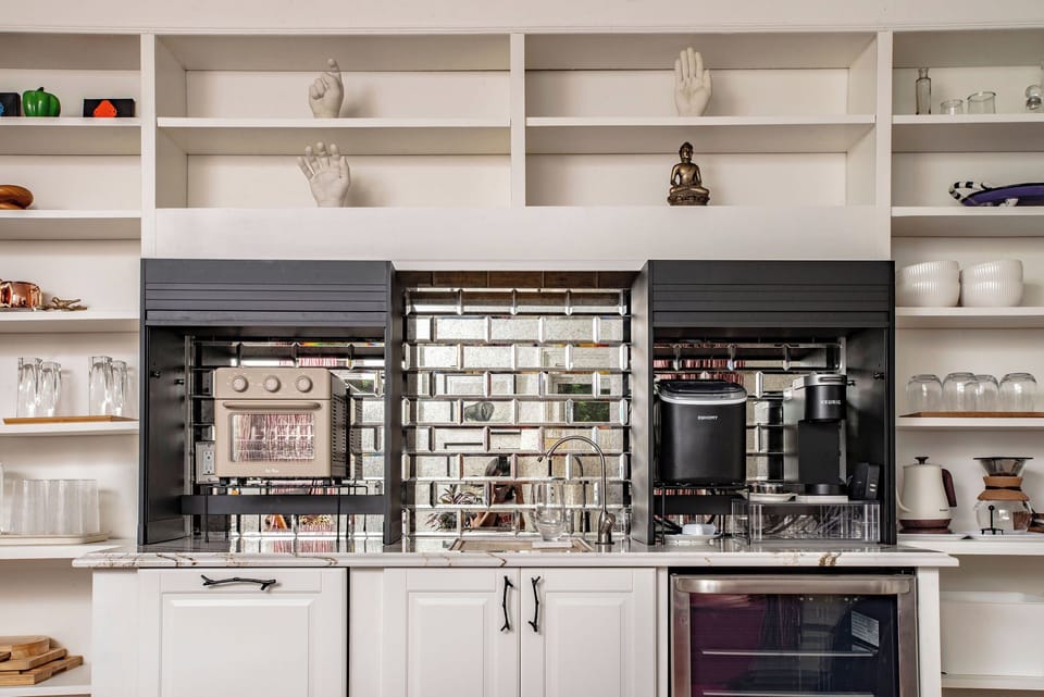 Close up of our kitchenette, featuring a mini-fridge, sink, ice maker, Keurig coffee maker, and toaster oven / air fryer.