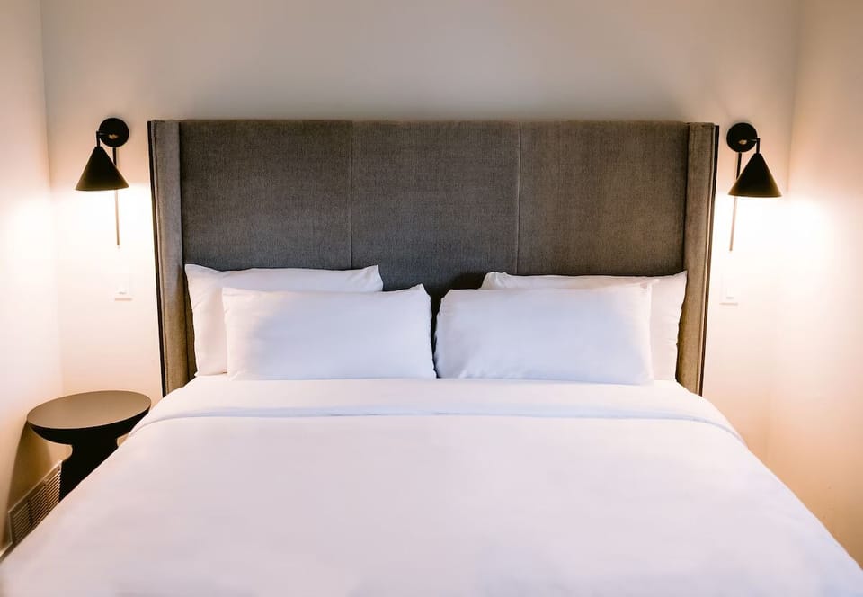 Drift off in a serene bed framed by warm bedside sconces.