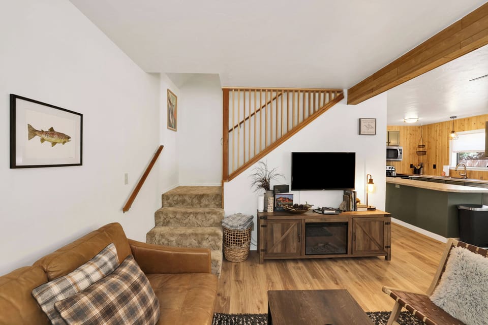 Cozy living room with plush seating, smart TV & forest-inspired decor.