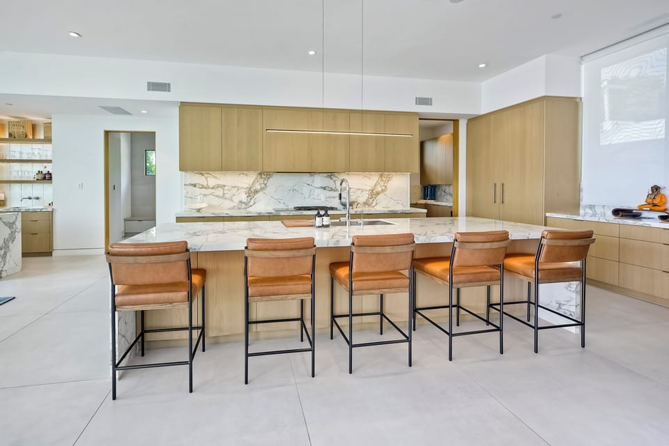 Gather around the oversized island with leather barstool seating in this sleek chef's kitchen