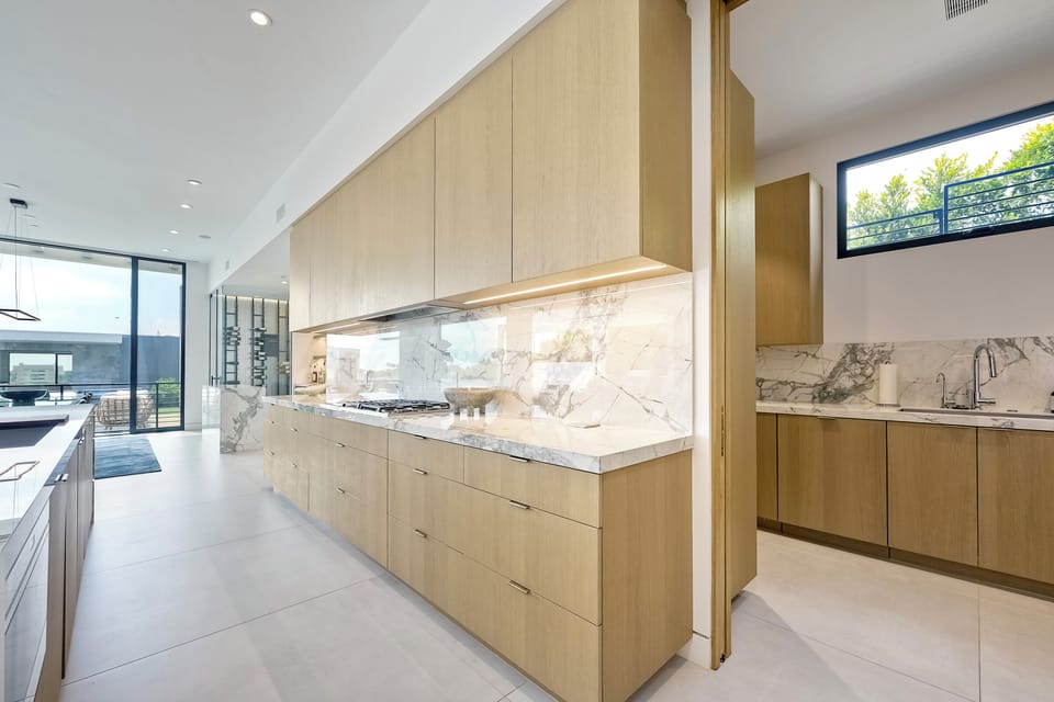 Streamlined cabinetry and marble finishes extend down the galley kitchen