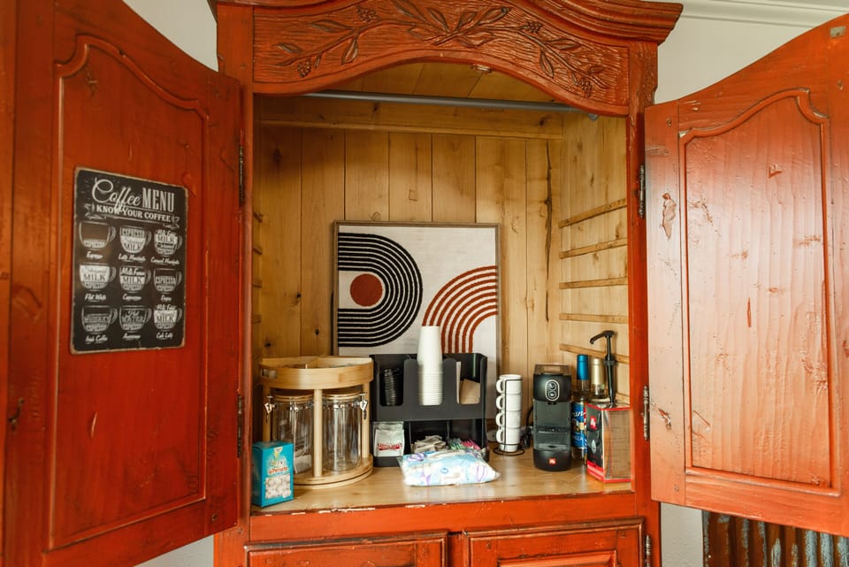 An armoire in the family sitting area has a well stocked coffee and tea bar