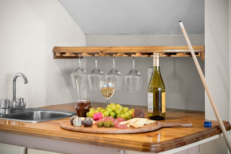 Your own mini wine bar awaits. Pour a glass, grab a bite, and rack up the fun—this cozy corner with hanging glasses, a sink, and charcuterie vibes is perfect for unwinding between pool shots and laughs.
