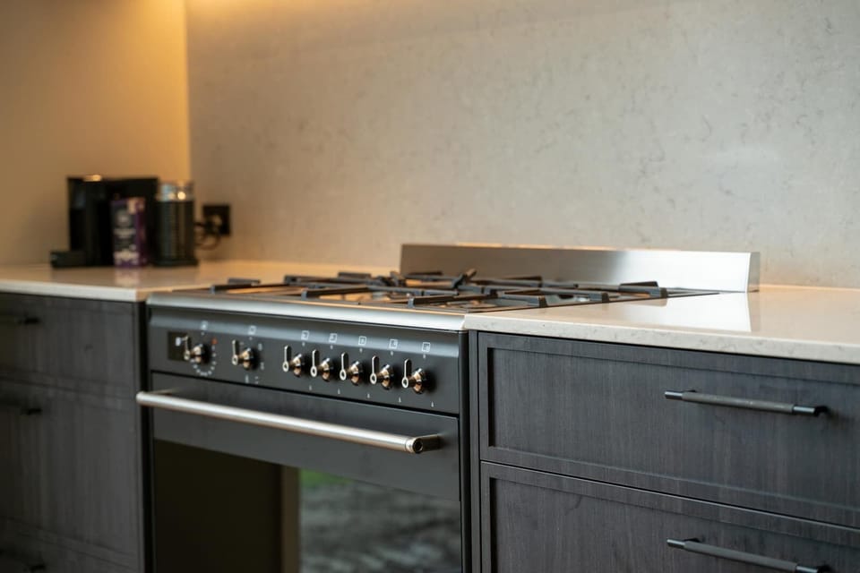 A high-quality gas cooktop and oven ready for family dinners or entertaining. Stylish black fixtures and subtle lighting add a modern touch.