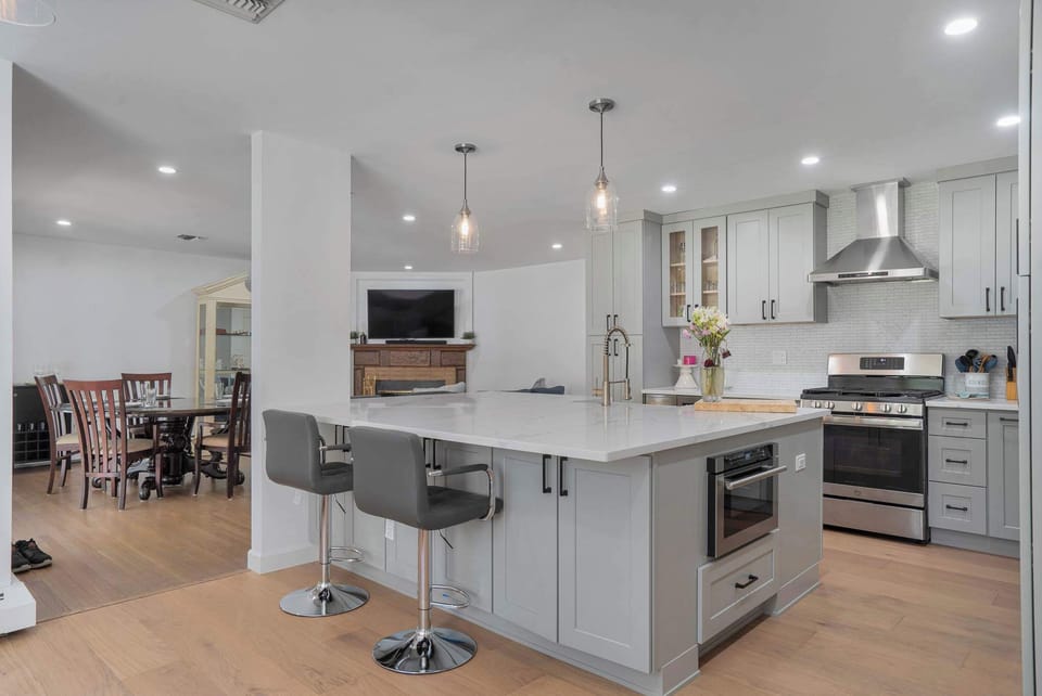 Renovated kitchen with quartz island, shaker cabinetry, and pendant lights