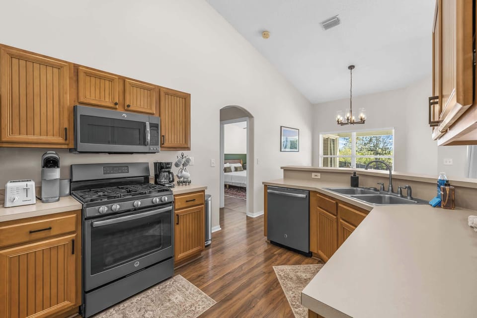Kitchen with wooden cabinetry, stainless steel appliances, and a view into the dining area.
