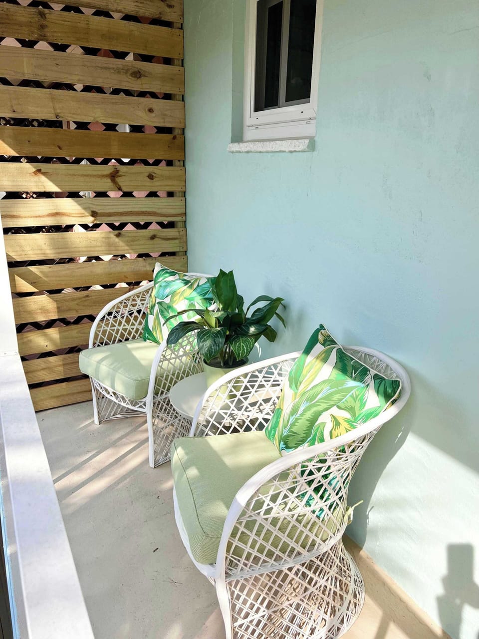 Cozy outdoor seating area with tropical-themed cushions and natural light.
