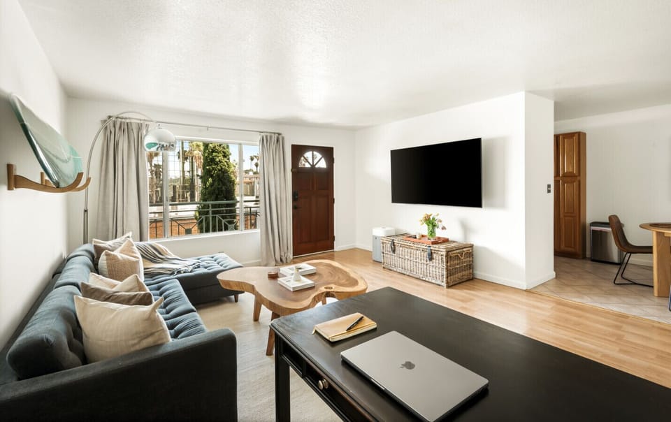 Comfortable and functional living room with a flat-screen TV and a sleek black desk—perfect for relaxing or catching up on work.