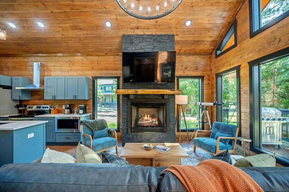 Relax on the plush sofa and take in the view through expansive windows, or cozy up with your favorite show on the smart TV beside the indoor fireplace — comfort and charm at every turn.