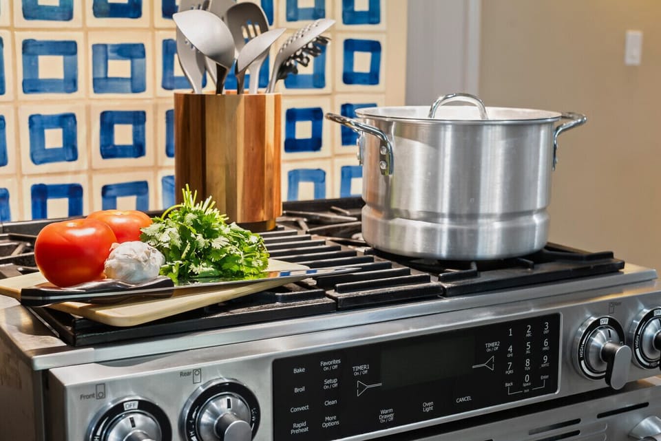 Fully equipped kitchen with a modern stove, essential pots, and cooking spoons—everything you need to prepare delicious meals.