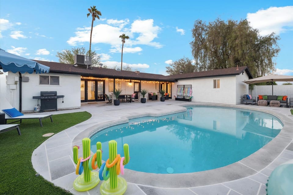 Fully fenced luxury private backyard with large pool, lounge chairs & umbrellas
