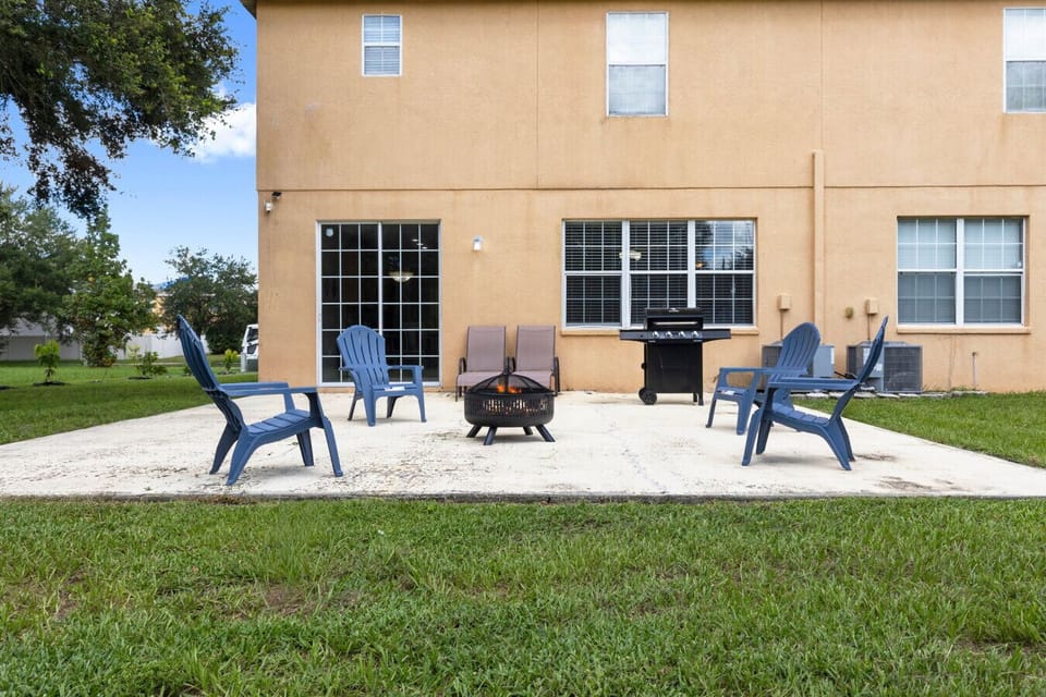Back Patio | Large concrete patio with seating, fire pit, lounge chairs, and grill, opening to spacious backyard