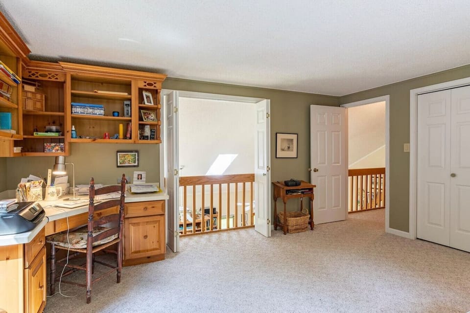Loft office area with built-in wood desk, shelving, and view into living space below.