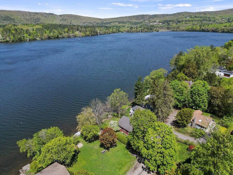 Breathtaking aerial view of the sparkling lake surrounded by lush greenery and rolling hills.