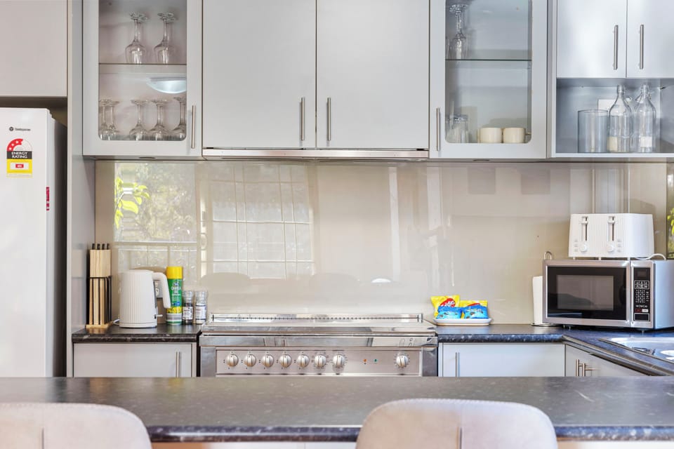Discover a sleek, modern kitchen, thoughtfully designed with ample gray cabinetry and sparkling countertops, creating an airy and bright space perfect for culinary adventures.