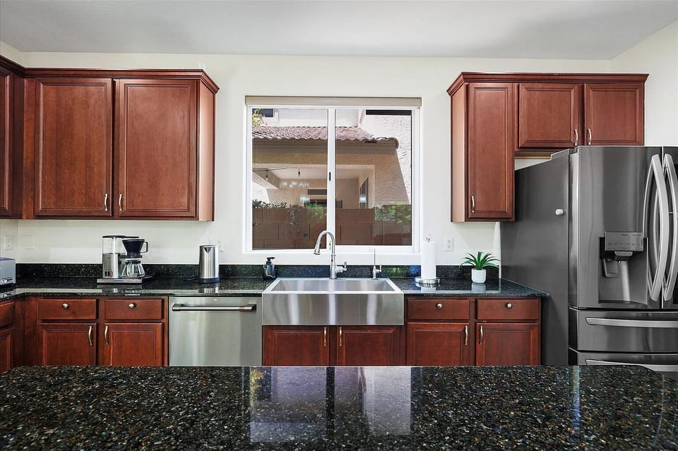Farmhouse sink with window view and stainless fridge, dishwasher, kettle