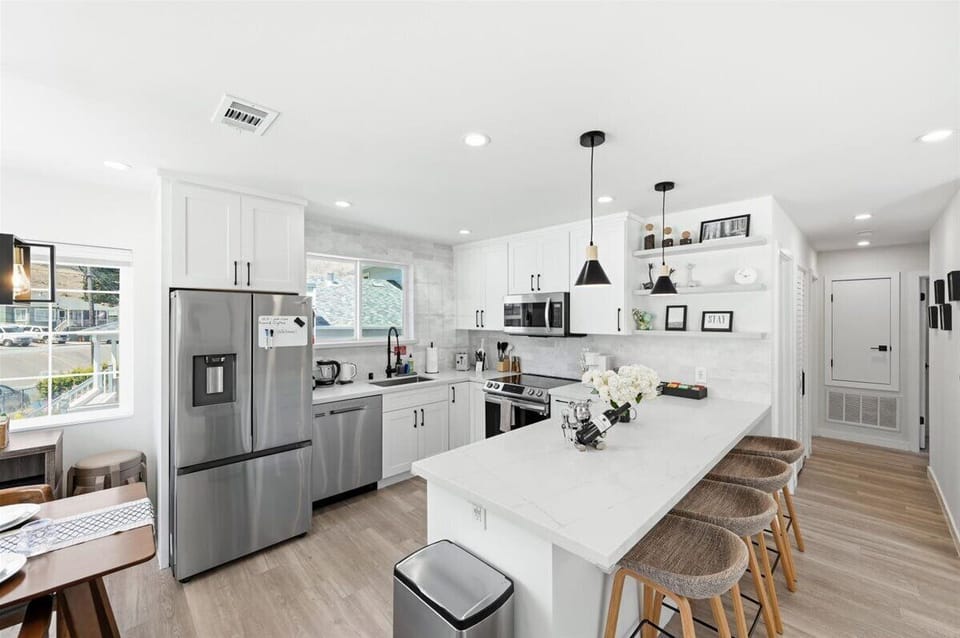 Modern open kitchen featuring white marble countertop and backsplash.