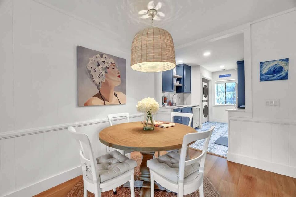 Cozy dining area with a round wooden table and modern blue kitchen in the background.