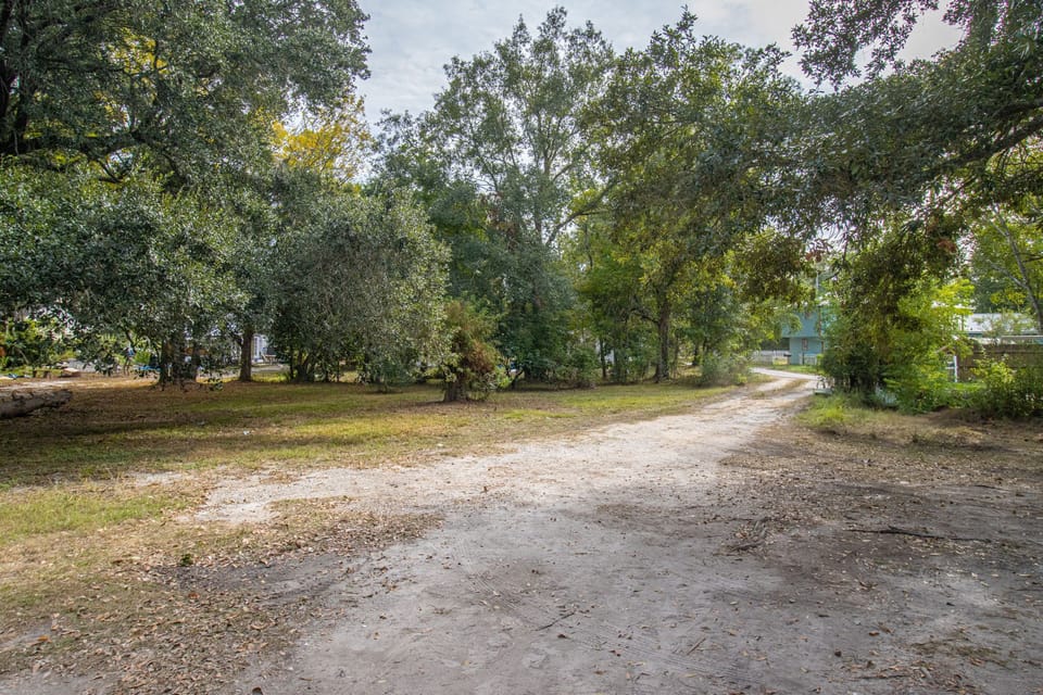 Experience a tranquil entrance to your pet-friendly Gulfport retreat, surrounded by lush trees along the sandy path.