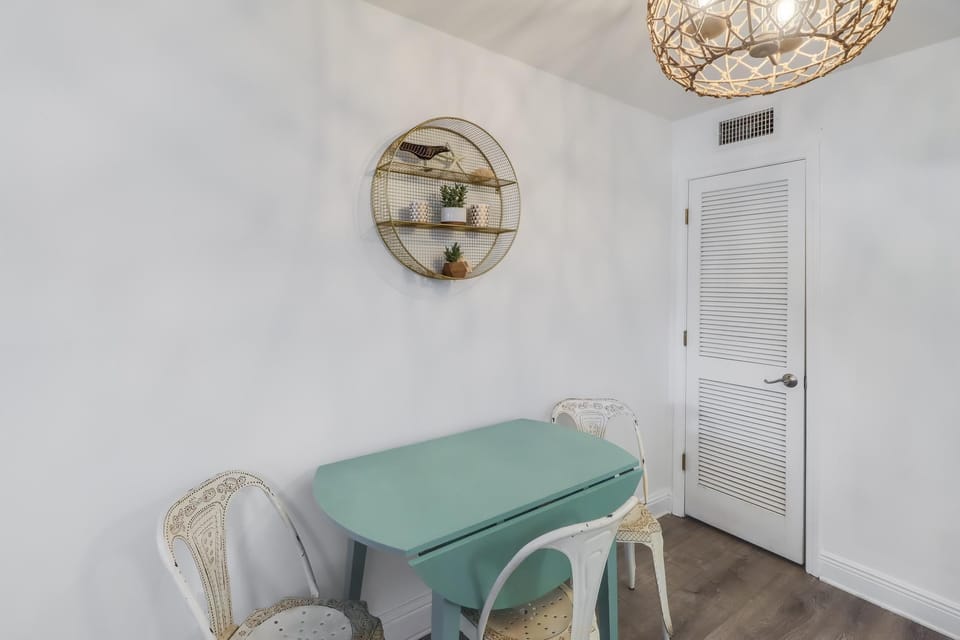 The dining area features a chic teal table and decorative touches, ideal for casual meals and gatherings.