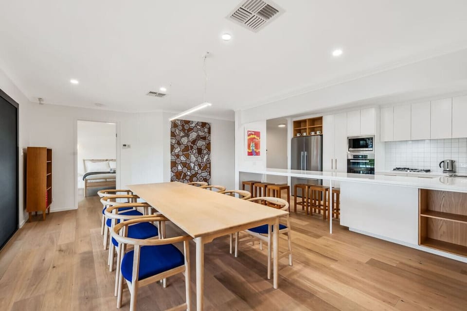 Dining area featuring a long timber table and seating for eight beside the kitchen.