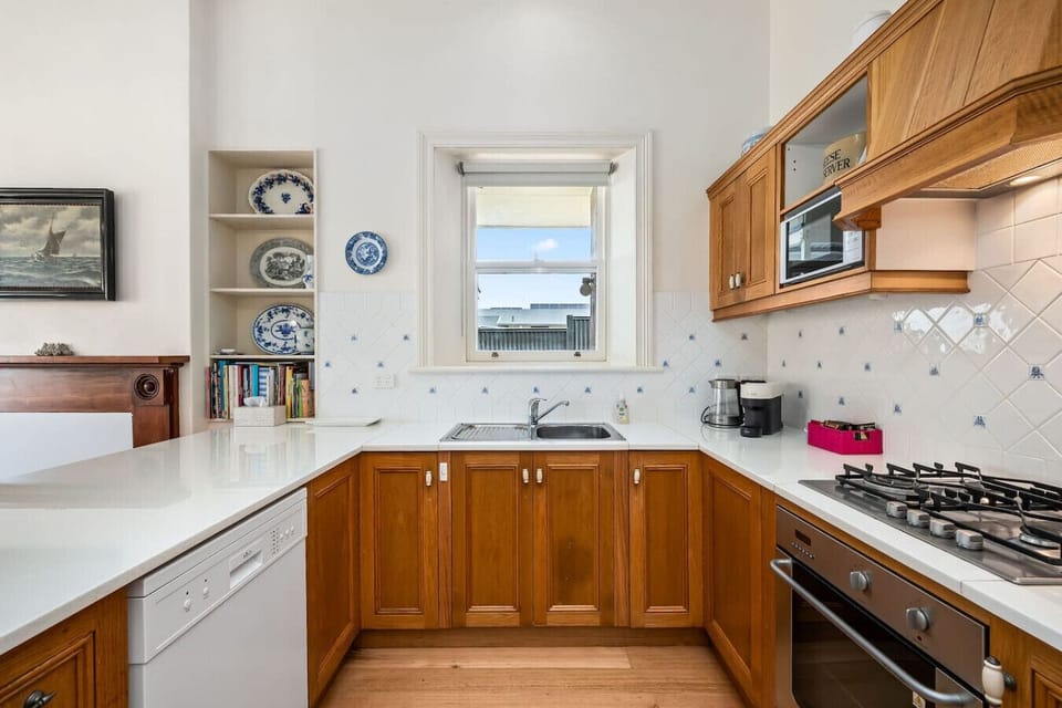 The well-equipped kitchen features a gas cooktop, dishwasher, and charming heritage details.
