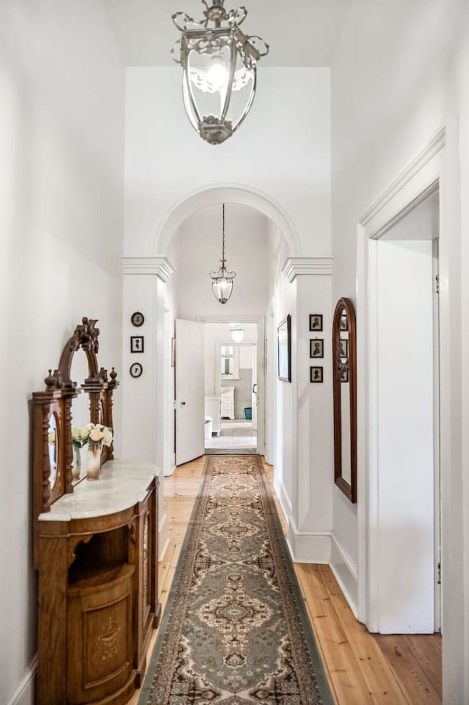 Grand hallway with period detailing, antique furnishings, and pendant lighting.